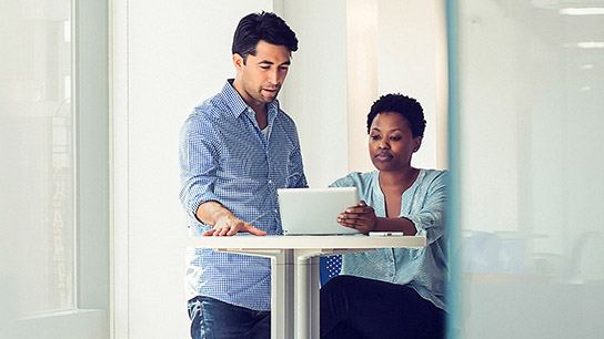 Two people in office environment viewing small wireless device